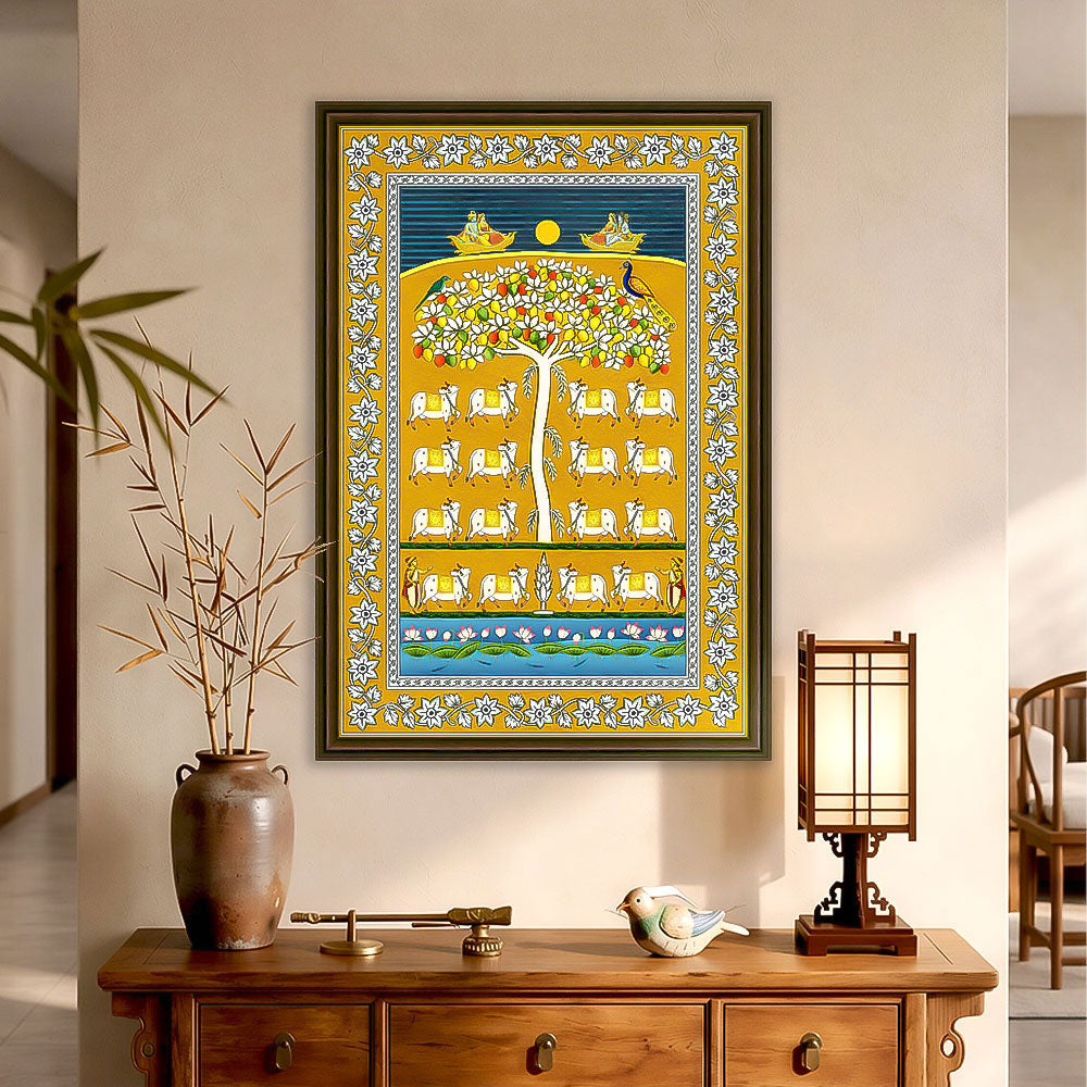 A framed vertical art print featuring a stylized tree of life with white deer and decorative borders, displayed on a beige wall above a wooden console table with a vase, decorative objects, and a lantern.