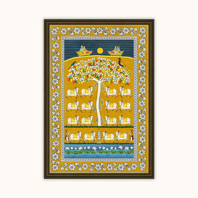 A framed Indian folk art print featuring a stylized tree of life with white cows, birds, and a yellow sun on a blue and gold background, enclosed in a dark brown frame.