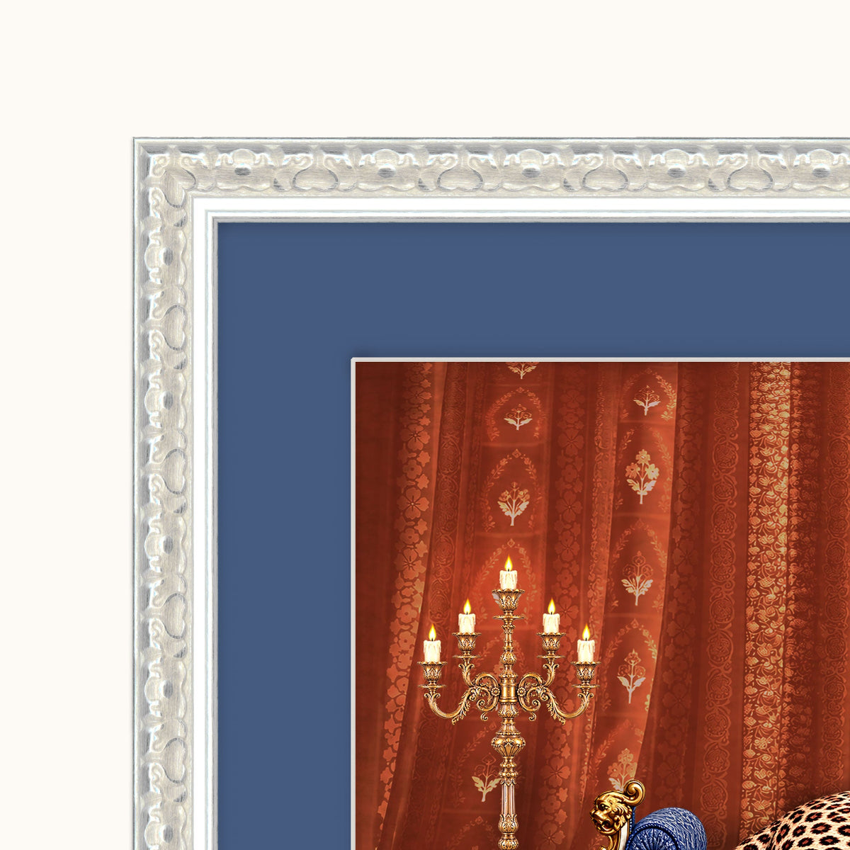 A close-up of a framed art featuring ornate red curtains, a gold candelabra, and a blue upholstered chair, surrounded by a wide blue mat and an ornate silver frame.