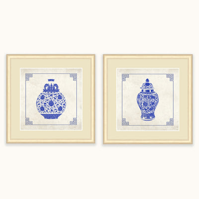 Two framed art featuring blue and white porcelain vase designs on a light beige background, displayed side by side against a white wall.
